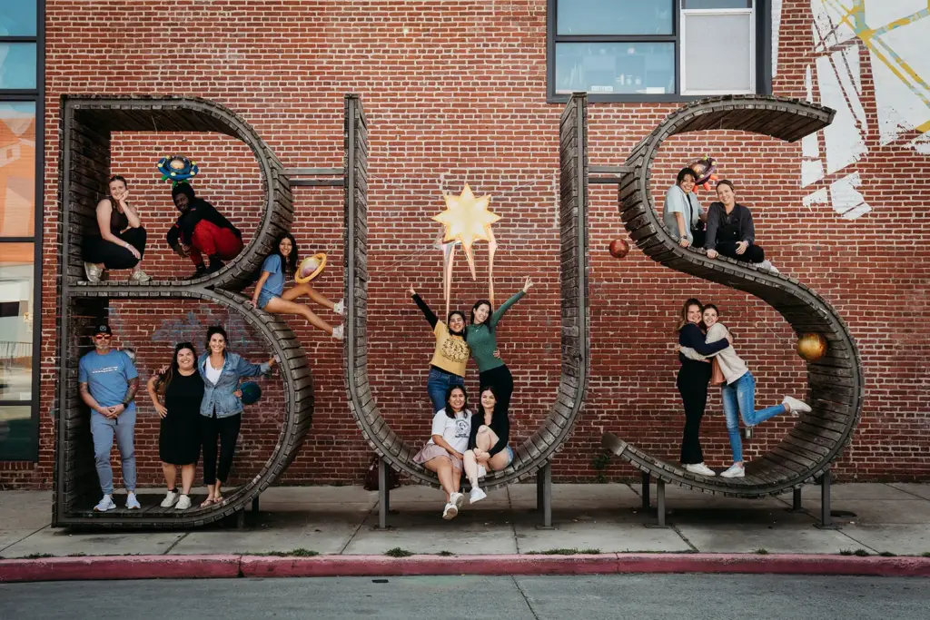A group of students at Baltimore Urban Studies posing in front of the BUS letter sign
