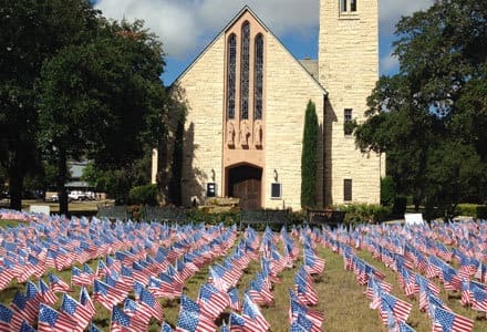 A field of American flags with TLU's Chapel in the background