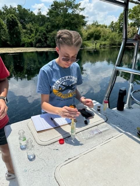 Student doing chemistry testing on river