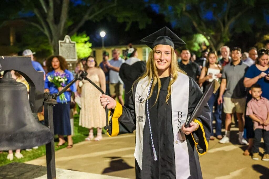 A TLU nursing graduate ringing the bell on graduation night.