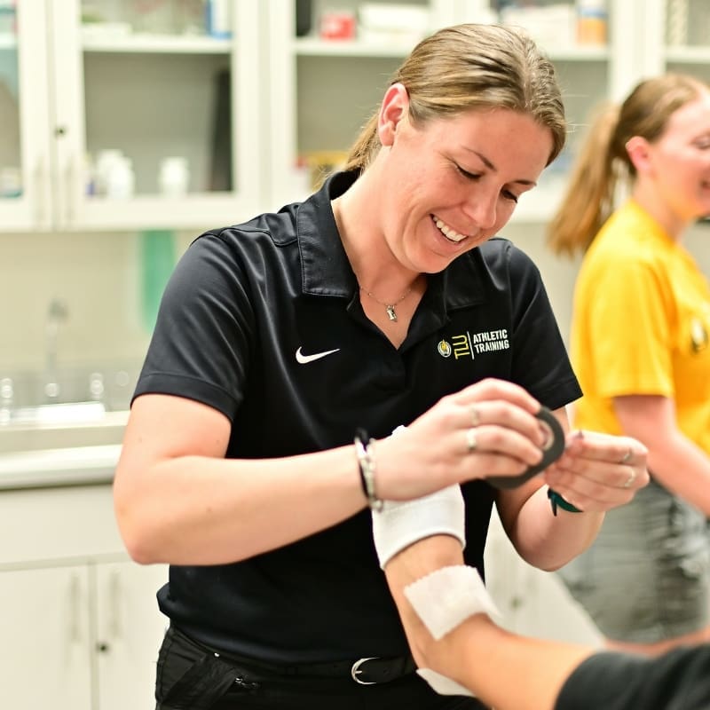 Image of a female TLU athletic trainer wrapping a foot injury