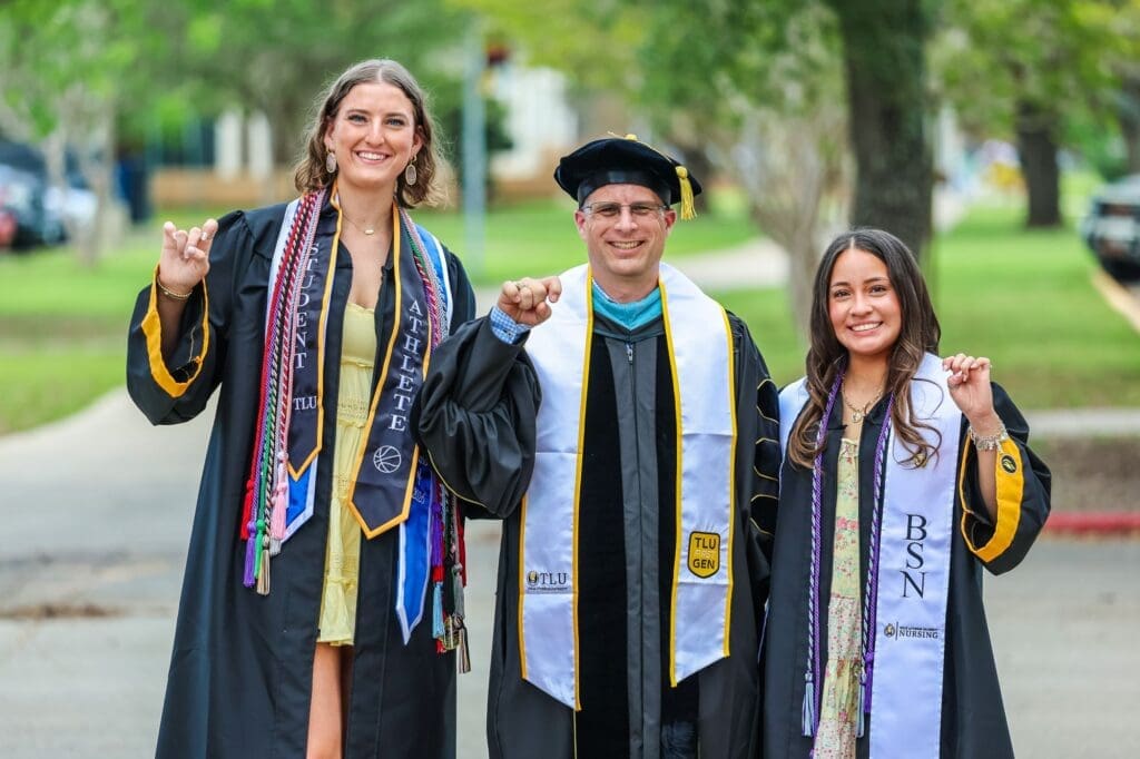 A professor and two graduates show their TLU spirit.