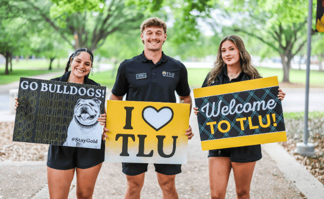 3 students with welcoming signs
